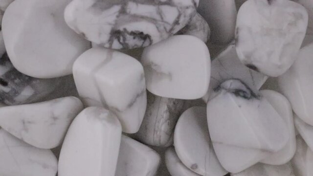 White turquoise is poured into a pile and spinning counter clockwise. Mineral pebbles background.