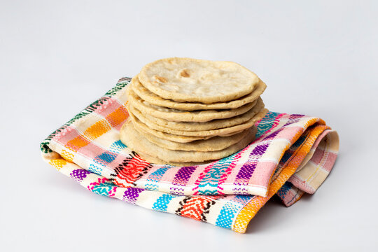 GUATEMALAN TORTILLAS STACKED AND PLACED ON A PATTERN NAPKIN ON A WHITE BACKGROUND
