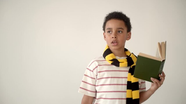 child holding the book while he is reading and memorizing
