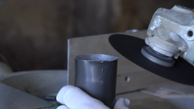 Master grinder grinds a pipe. The fitter cleans the edge of the pipe.