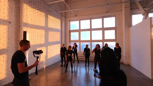 Timelapse. Photographers are taking pictures and video of the girls group performing modern shuffle dance in the studio
