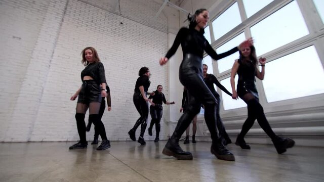 View from below of cute teenagers in black costumes performing modern shuffle dance in the studio