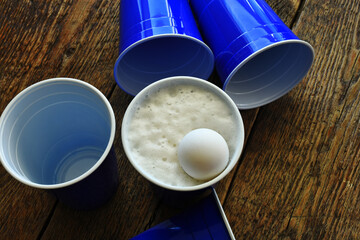 A close up image of blue plastic drinking cups with light beer ready  for a drinking game. 