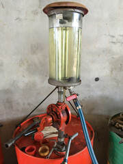 Fuel dispenser machines and large metal barrels with gasoline at a filling station.