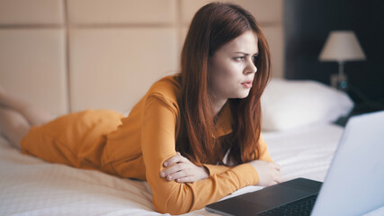 emotional woman in the bedroom lying on the couch with a laptop communicating