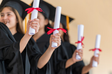 group of graduates Asian student in academic gown and graduation cap holding diploma