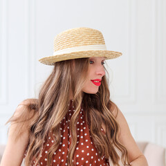 Portrait of a beautiful young woman in a hat against a white wall background