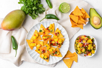 Composition with fresh mango salsa and nachos on light background