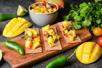 Crispbreads with fresh mango salsa on dark background