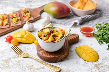 Composition with fresh mango salsa, crispbreads and nachos on light background