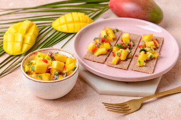 Plate with crispbreads and fresh mango salsa on color background