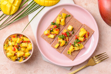 Plate with crispbreads and fresh mango salsa on color background