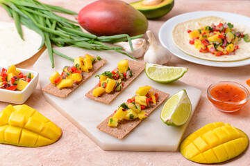 Composition with fresh mango salsa and crispbreads on color background