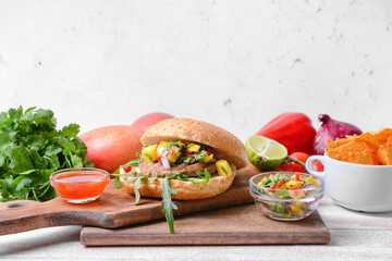 Composition with burger, fresh mango salsa and nachos on table