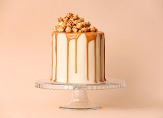 Tasty cake with popcorn and caramel on color background