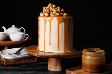 Tasty cake with popcorn and caramel on dark background