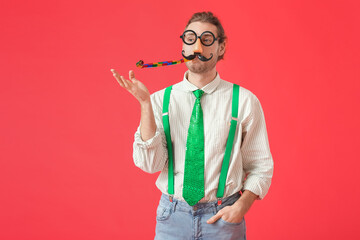 Young man in funny disguise on color background. April Fools Day celebration