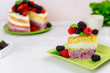 Piece of berry cake decorated with fresh raspberries and blackberries.