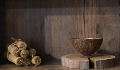 unusual decor and interior items, on a wooden stand made of wood there is a wooden bowl, next to it there is a bunch of interesting handmade candles, a background made of wood.