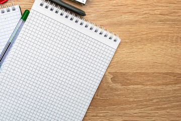 two notepads a paper clip a stapler and a fountain pen are on the table