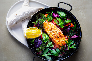 Pan fried salmon fillet with fresh salad and wrap muted background top down view. Healthy food.