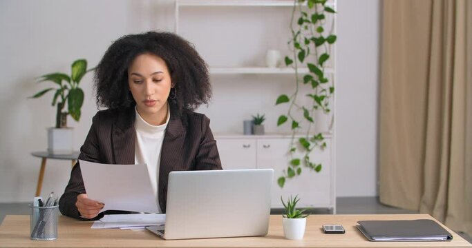 Afro american business woman receives letter from bank reads information bad results gets upset feels resentment frustrated sees finds mistake in financial report throws out document typing on laptop