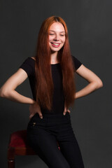 Fototapeta na wymiar studio portrait of a young red-haired woman in black clothes on a black background