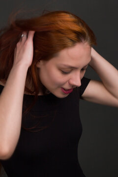 Studio Portrait Of A Young Red-haired Woman In Black Clothes