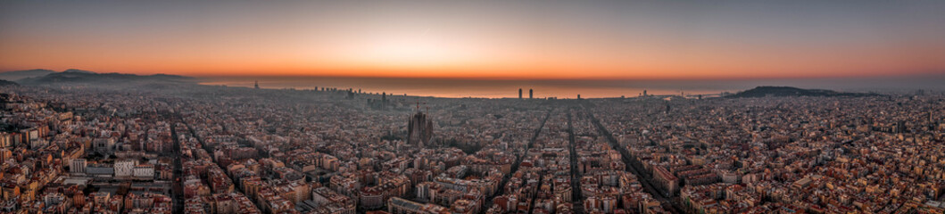 Naklejka premium Aerial panorama drone shot of Barcelona with sunrise over sea horizon in Spain winter dawn