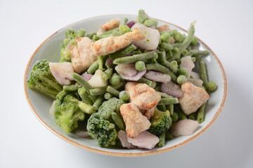 Frozen vegetable mixture of carrots, broccoli ,peppers, red onion and peas with pieces of cut chicken fillet. Healthy food