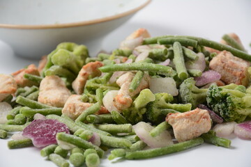 Frozen vegetable mixture of carrots, broccoli ,peppers, red onion and peas with pieces of cut chicken fillet. Healthy food