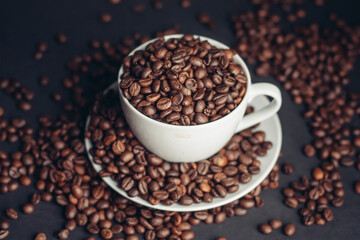 coffee beans In a saucer and in a cup of coffee on a gray background female hand macro photography