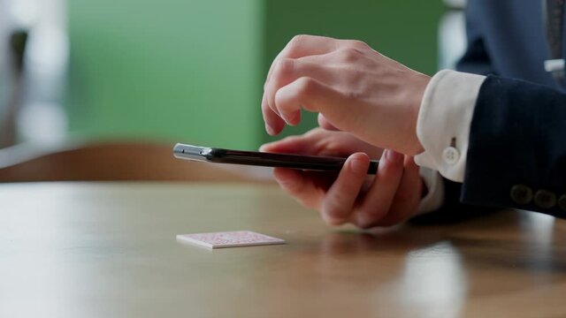 Close-up of smartphone in male hands tapping on screen. Unrecognizable man scanning QR code on table in restaurant or cafe. Online menu for clients. Convenience concept.