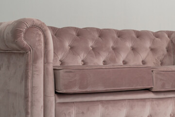 a classic pink sofa sits in a white room on a wooden floor. copy space