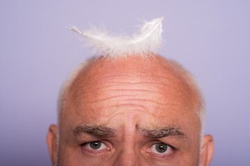 Senior old aged head of bald man. Hair loss, baldness with feather.