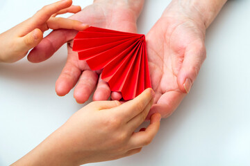 Childs hands give gift box to grandmother. Congratulations with present for mothers day or National Senior Citizens Day. World Humanitarian Day