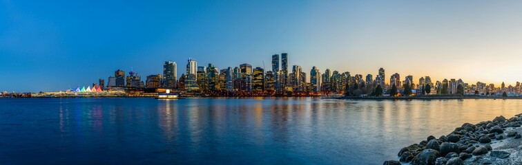 Night view of Vancouver downtown skyline panorama after sunset. Colorful buildings lights reflections on waterfront harbor. British Columbia, Canada.
