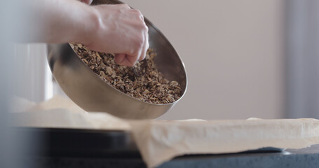 man making granola pour it on baking tray with parchment paper