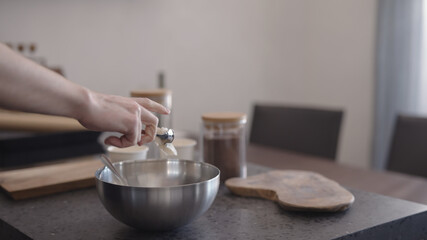 Man making granola add coconut butter into steel bowl on kitchen countertop