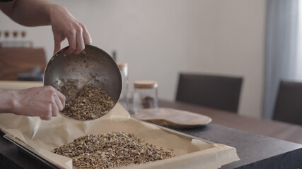 man making granola pour it on baking tray with parchment paper