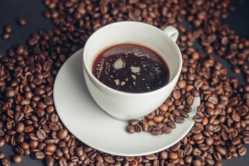 coffee beans and a cup on a white saucer dark background drink