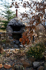 outdoor stone fireplace at their summer cottage against the background of a rose branch