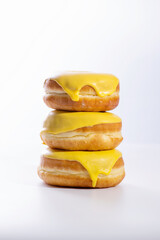 three donuts with banana filling lie in a stack on a white background, delicious breakfast, bright mood