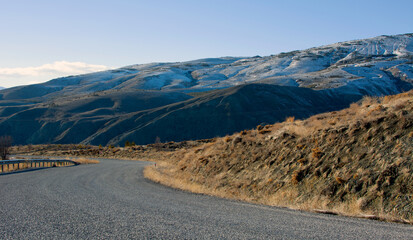 asphalt road on the mountain and snowy hill opposite.outdoor and travel background.