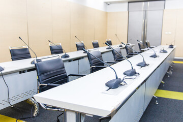 Empty meeting room and conference table with microphones and chairs
