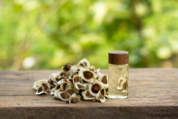 Oil of Moringa in bottle with seeds on wooden and blur background. Moringa oleifera tropical herb product concept.