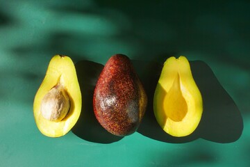 shiny sliced avocado in green background with shadow in hard light photography