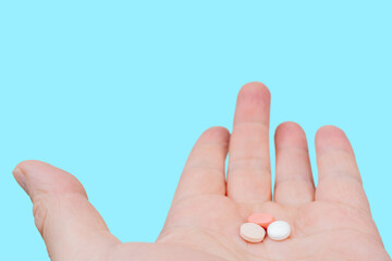 White and pink pills in the palm of your hand. Treatment with pills.