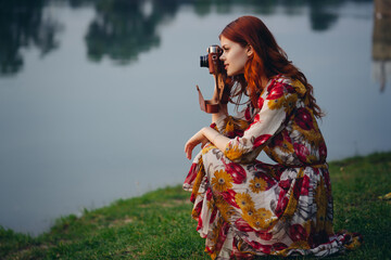 Obraz premium red-haired woman with a camera in nature near the lake