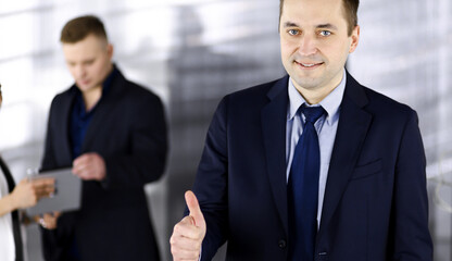 Fototapeta premium Portrait of a successful middle aged businessman, who is enjoying a good result of a teamwork, while standing at meeting in an office. Concept of success in a business